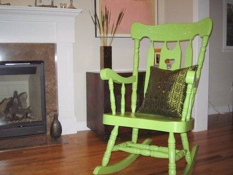 Green color wooden rocking chair with a pillow.