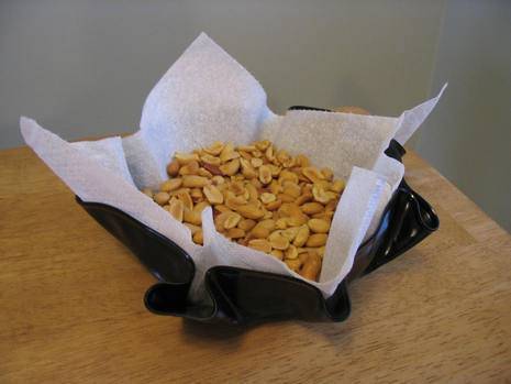 Nuts are on a paper in a black bowl.