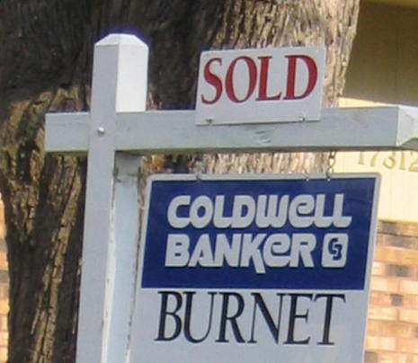 A sold sign is on a Caldwell Banker sign.