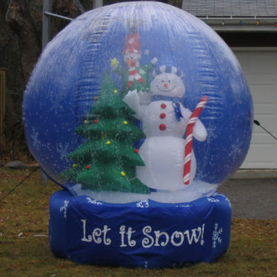A giant inflatable snow globe with a snowman and a Christmas tree inside.