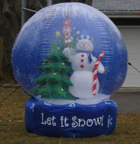 A giant inflatable snow globe with a snowman and a Christmas tree inside.