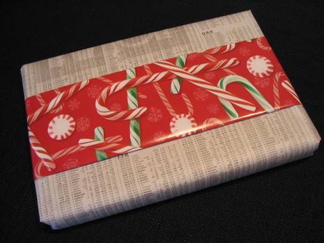 Book wrapped in plain wrapping paper with strip of candy cane decorated wrapping paper in middle.