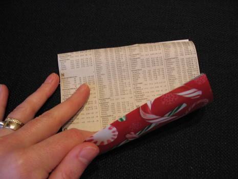 A person is rolling up a piece of red paper.