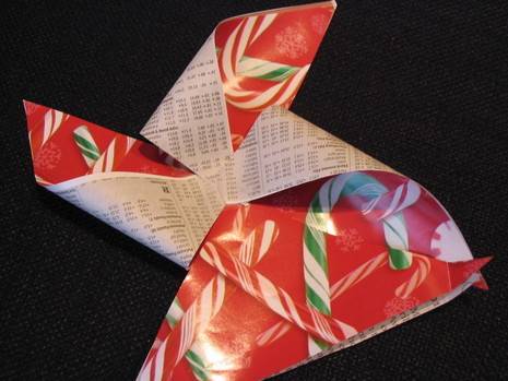 A bow made of red wrapping paper with a green and red candy cane pattern.