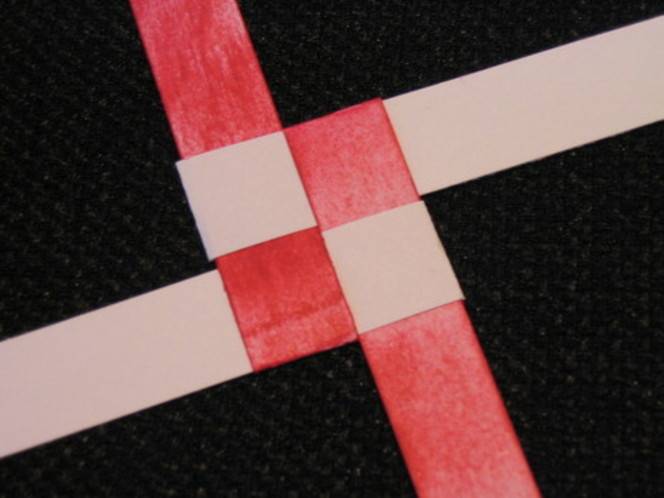 Two brown strips of paper and two red strips of paper in a basket weave.