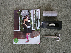 A J. Crew magazine is next to string, tape and scissors.