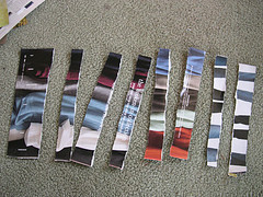 A colorful page has been cut into strips and laid out on light gray carpet.