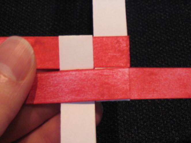 A person is holding red and pink strips of paper.