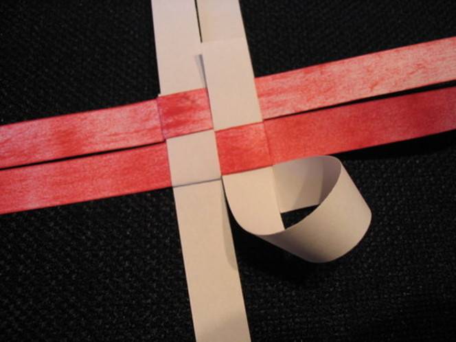 Pink and red ribbons are spread across a black surface.