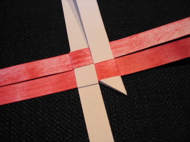 Pink and red ribbons criss cross on a black surface.