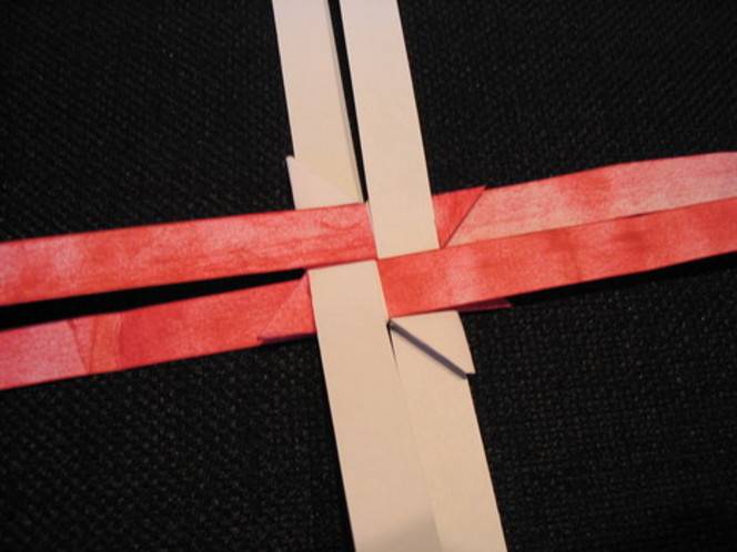 Two brown strips of paper interlaced with two red strips of paper.