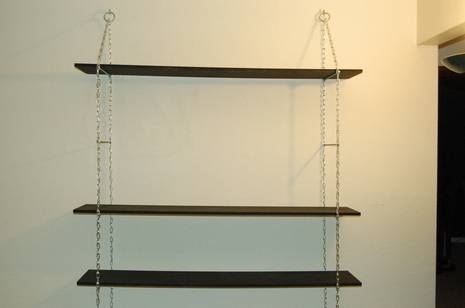 Hanging bookshelf with wooden racks and chains.