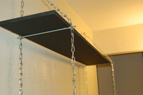 "The bookself is hanged on the wall using a chain and supporting rod ".