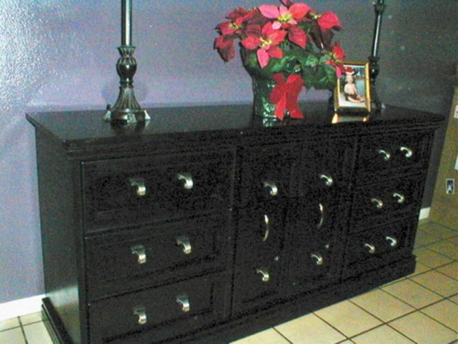Poinsettia next to candlesticks and picture frame on top of black buffet.