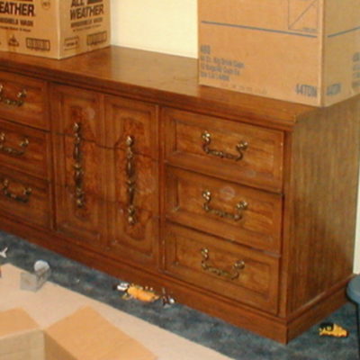 A brown dresser little toys scattered at the base and with two carboard boxes on it.