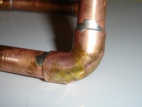 Rusty copper pipe with lead soldering.
