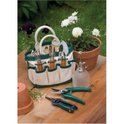 A gardening kit and flower pot next to tools on a table.