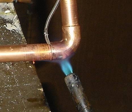 A copper pipe is being welded with a machine.