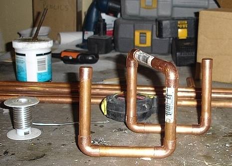 Copper pipes on top of solid surface next to tool box and plastic container.