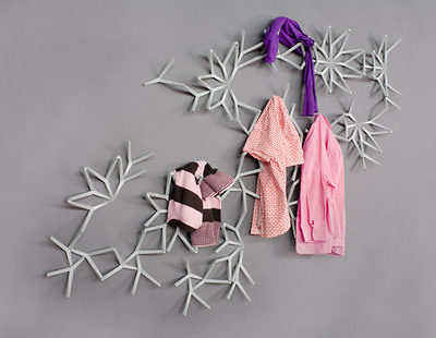 An aray of triangular pieces with two pink shirts, one pink and black shirt and a purple piece of clothing hanging on it.