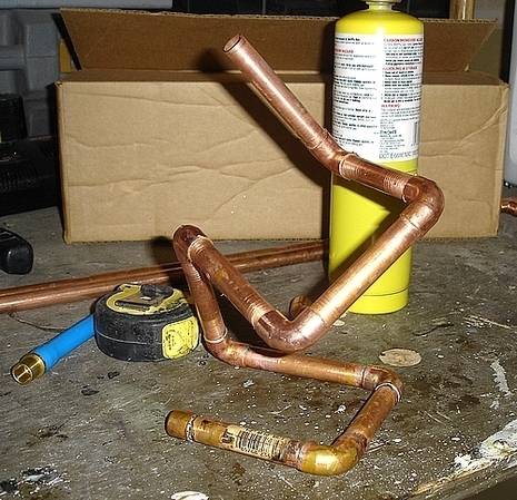 Copper pipes next to measuring tape and butane torch.