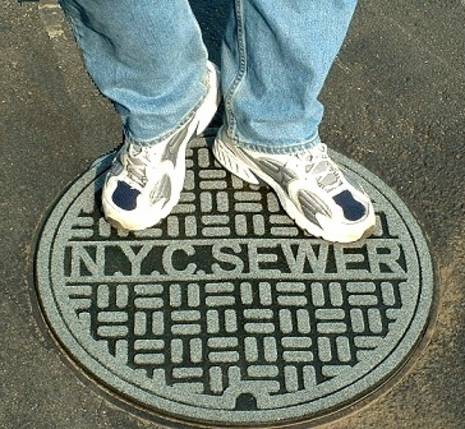 A man standing in sewage lid.