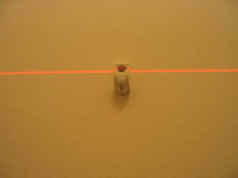 A lazer level marks a straight line on the wall.