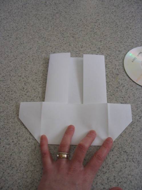 Person folding paper to prepare folded paper CD case.