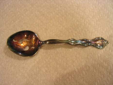 Antique metal spoon with tarnished surface.