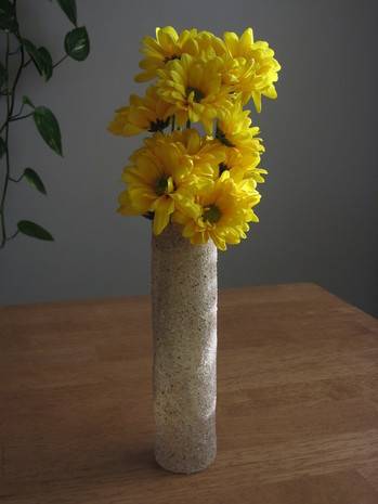 Bouquet of flowers in tall, thin vase on top of a table.