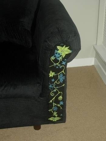 Couch with embroidered floral design on arm in a living room.