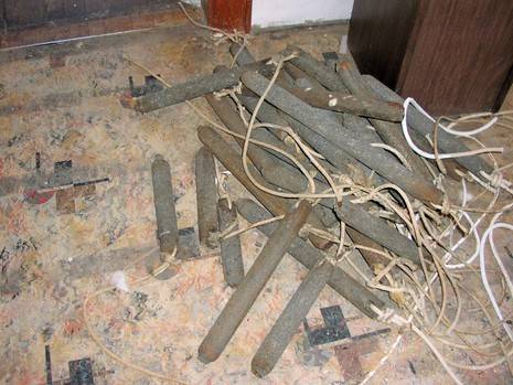 Group of thin wood sticks interlaced with string on top of a cement floor.