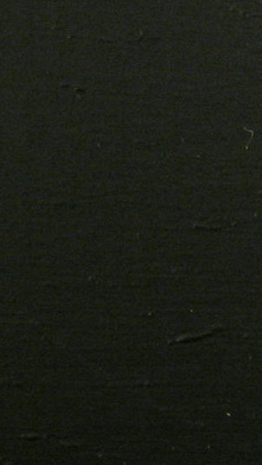 Black paper with ripples on top of flat surface.