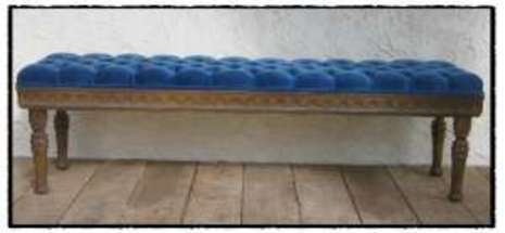 A long antique bench which blue plush padding.