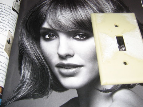 A light switch cover on top of a black and white photo of a female model.