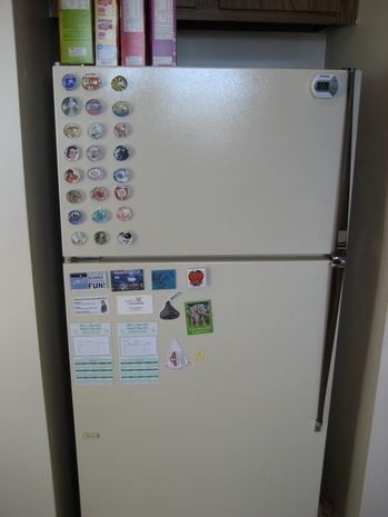 Cereal boxes on top of refrigerator with aligned magnets in a kitchen.