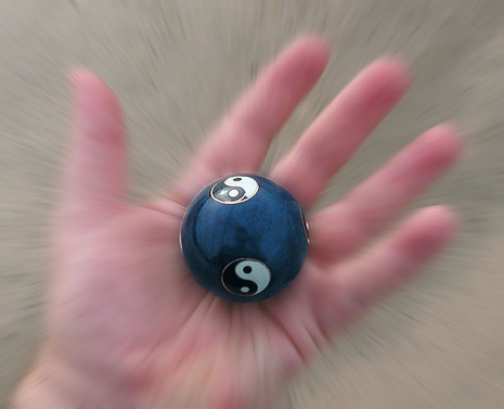 A person is holding a blue ball with a yin yang sign.