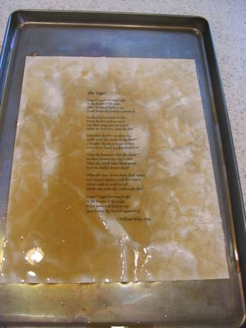 A poem on a page covered in brown liquid on a sheet pan.