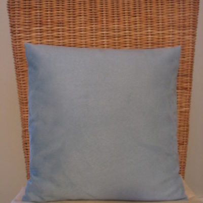 Square pillow on chair with wicker back.