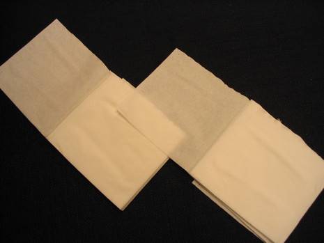 Two brown sheets of paper towel are sitting on a black surface.