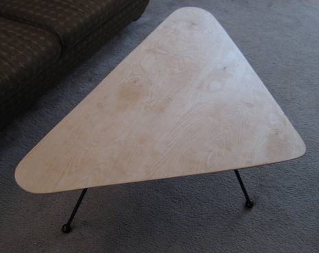 A triangle shaped table has a wispy design on top.