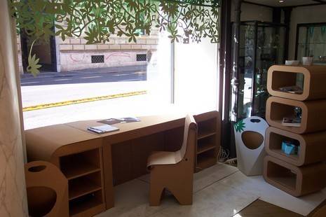 A wooden table sits near a wooden desk near a big window.