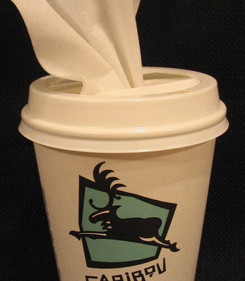 A white napkin pokes out from the lid of a Caribou Coffee cup.