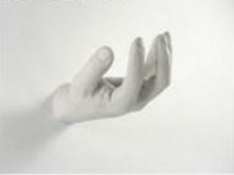 A person is holding out their hand in a white room.