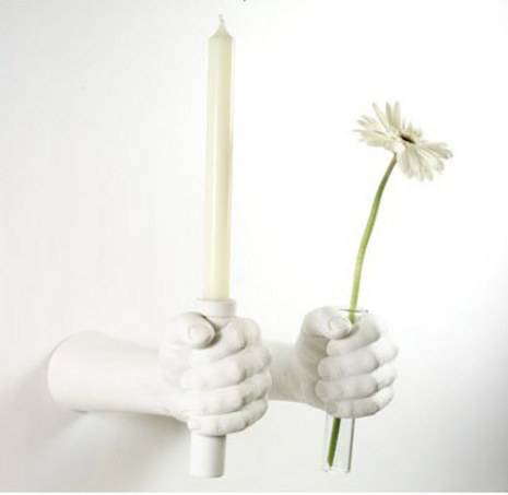 Ceramic hands holding candle and flower.