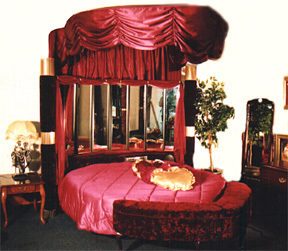 A fancy red and black bed with a satin overhang.