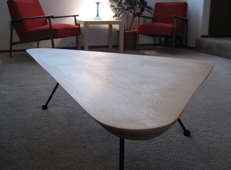 A triangular table with three black legs.