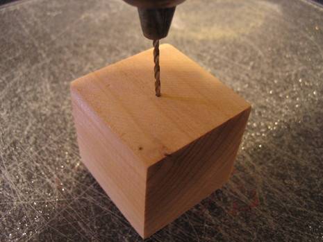 A person is drilling into a block of wood.
