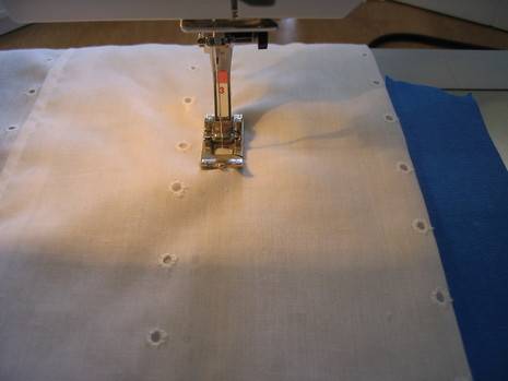 A white cloth is being sewed with a small machine.
