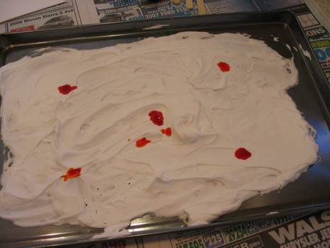 Shaving cream interspersed with red dye dots in a metal tray.